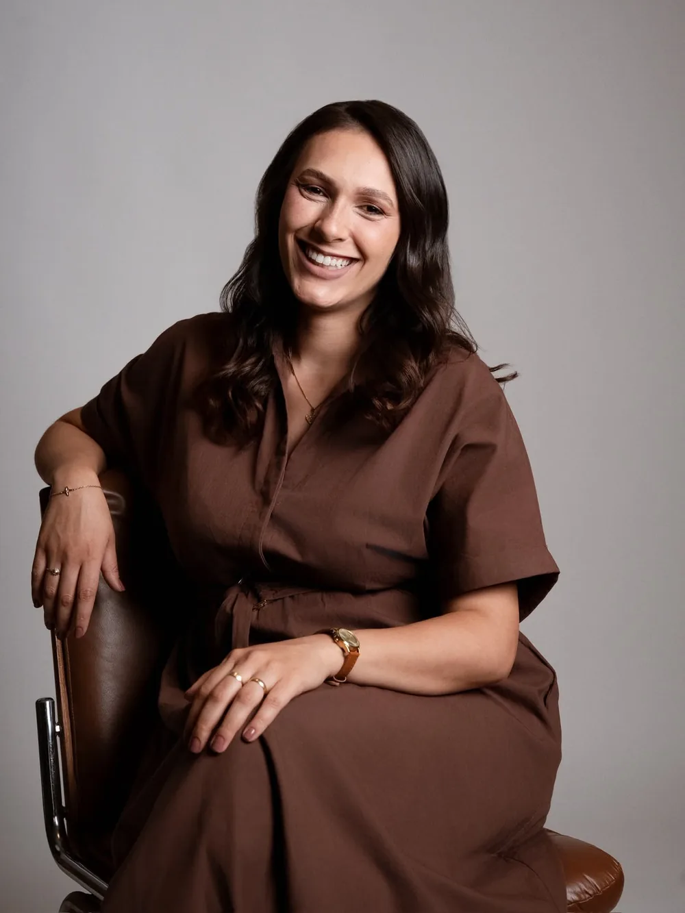 Retrato da psicóloga clínica Carla Parreira sorrindo, sentada com as mãos sobre o joelho